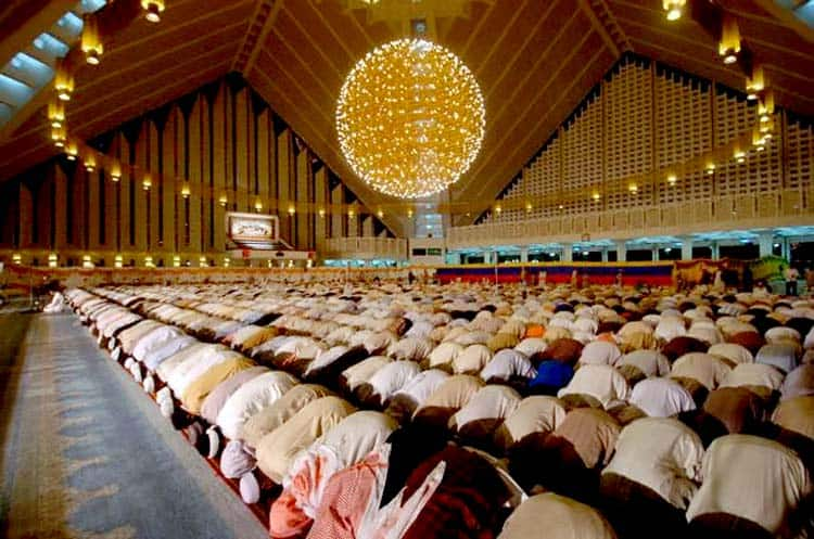 Worshippers praying during Taraweeh in a beautifully lit Saudi mosque - (Credits QuranReading.com)