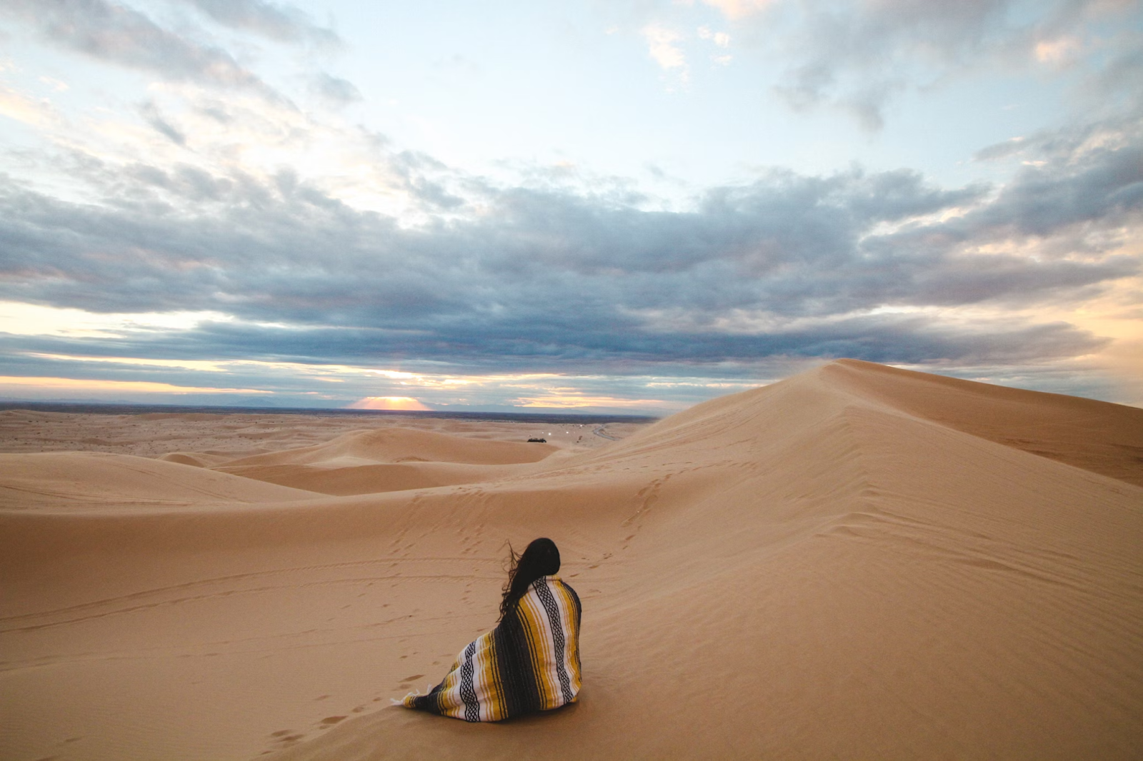 A woman covered in a shawl exploring a desert in Saudi Arabia - (Credits Unsplash)