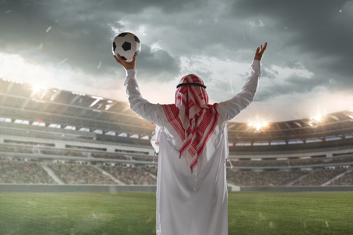 An Arab man holding a football in his hand in a football stadium - (Credits Wired Middle East)